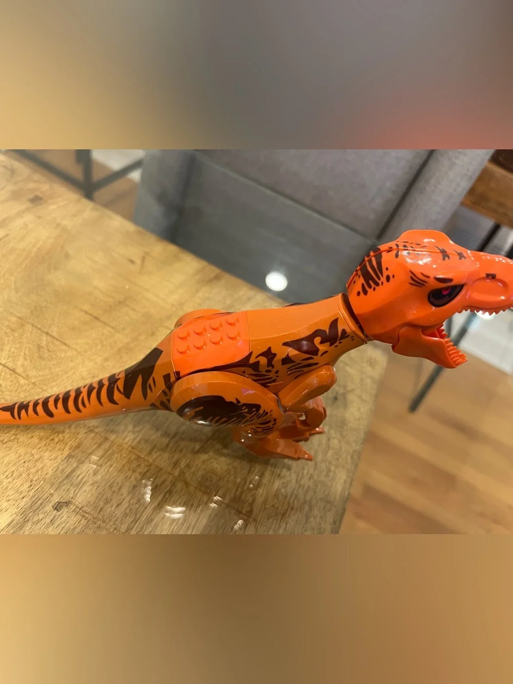 orange-and-brown molded plastic Tyrannosaurus Rex dinosaur makes noise building